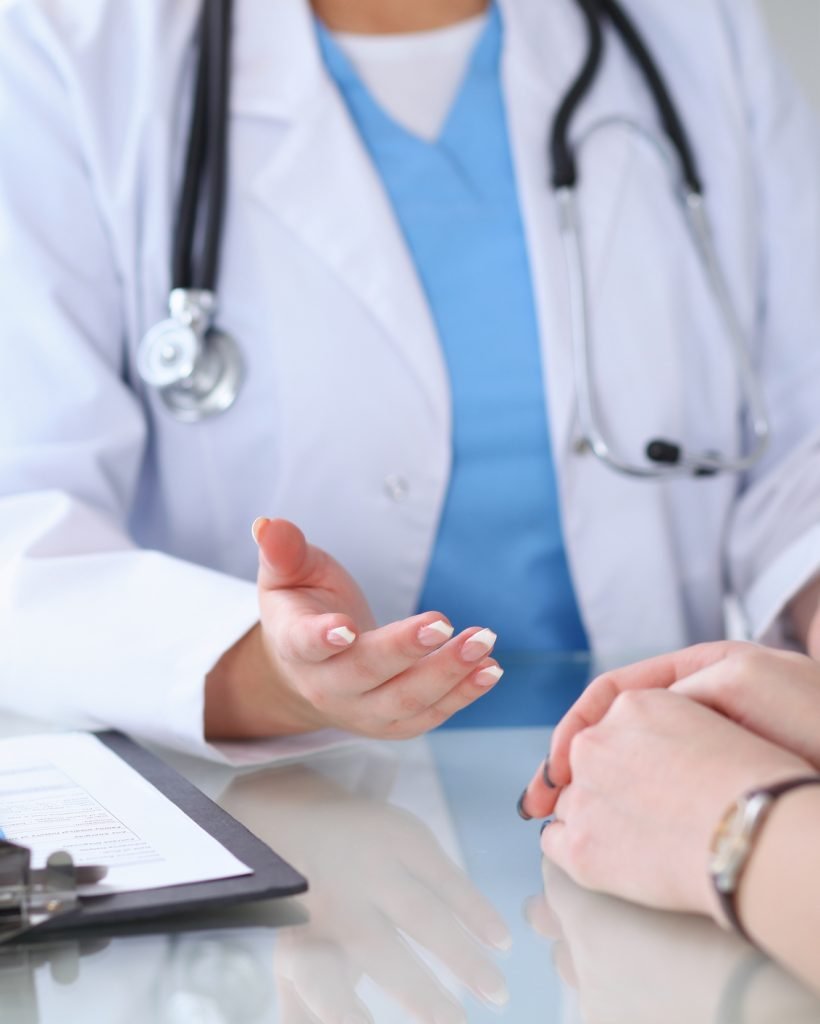 Close up of a doctor and  patient hands discussing something while sitting at the table . Medicine and health care concept